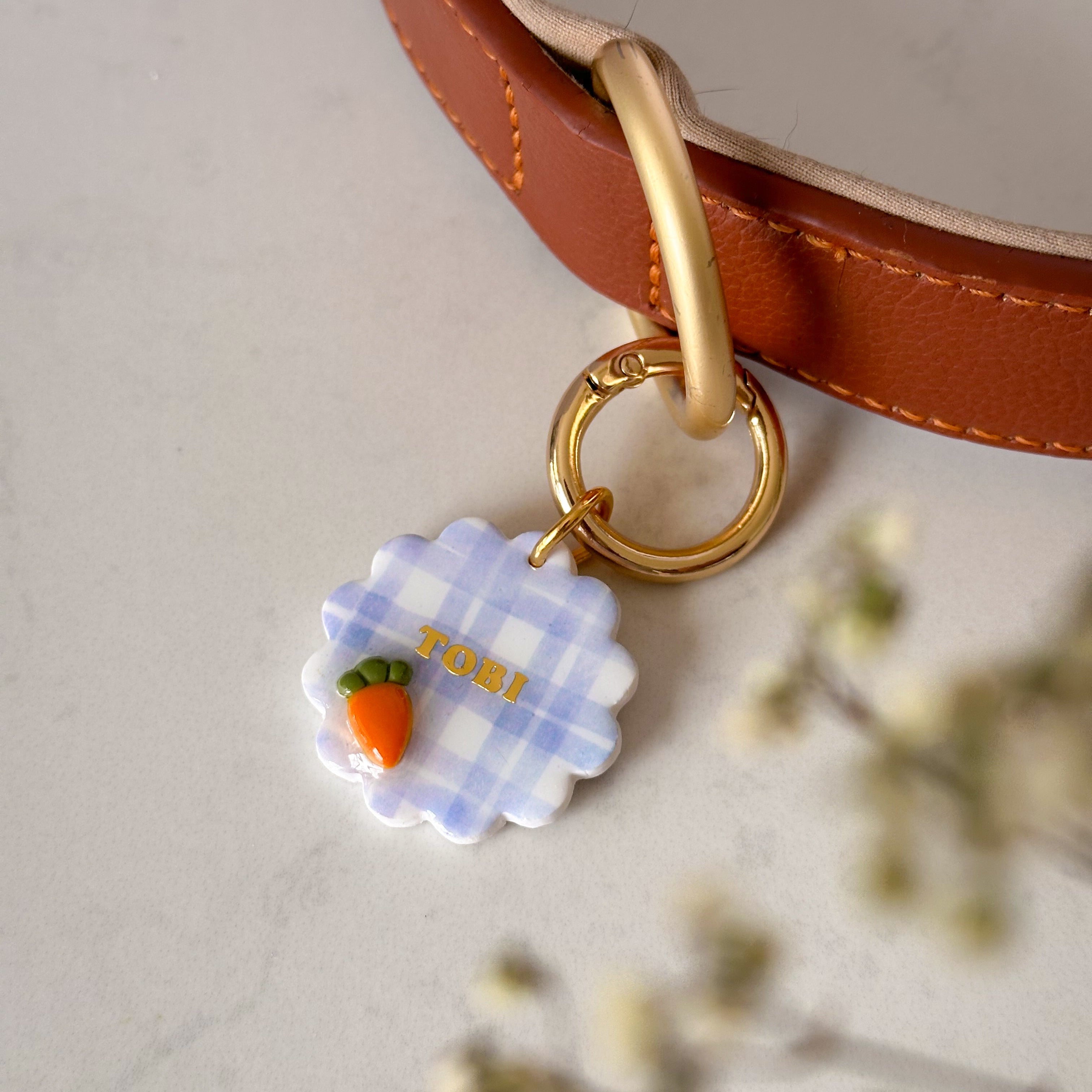 Dog collar with a checkered flower pet id tag on a light background