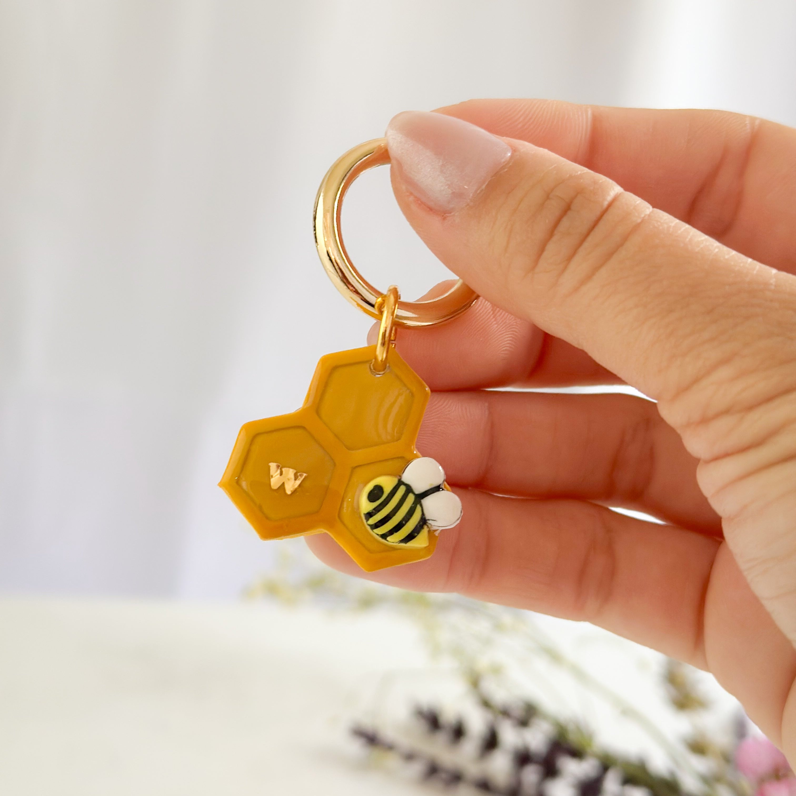 pet id tag with a bee and honeycomb design against a blurred background